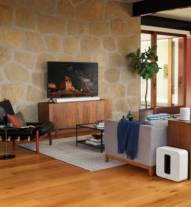Sonos Arc Black под телевизором на фоне каменной стены &mdash; демонстрация в стильном интерьере